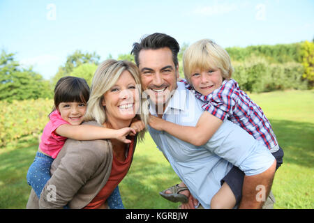 Les parents qui piggyback ride to kids in park Banque D'Images