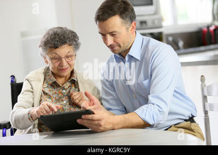 Homme avec femme âgée using digital tablet Banque D'Images