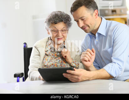 Homme avec femme âgée using digital tablet Banque D'Images