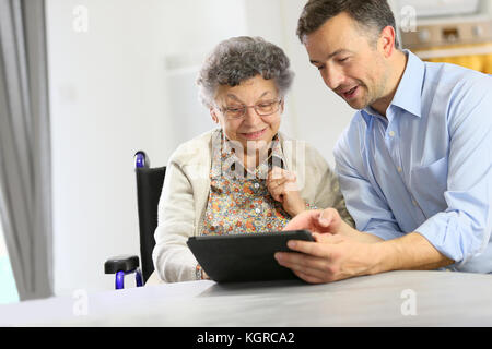 Homme avec femme âgée using digital tablet Banque D'Images