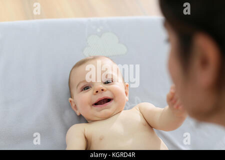 Maman jouer avec bébé garçon tout en changeant les couches Banque D'Images