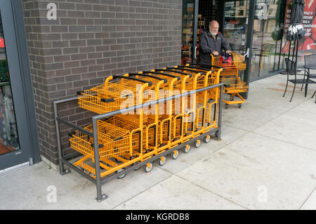 Vieil homme poussant une orange panier métallique à l'extérieur d'un magasin à Vancouver, BC, Canada Banque D'Images