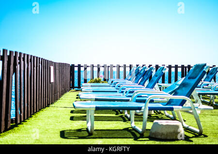 Une rangée de chaises longues sur une station balnéaire sur la Méditerranée sous un ciel bleu clair Banque D'Images