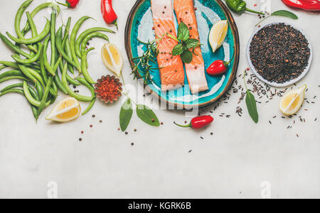 Télévision à jeter des filets de bœuf Poisson saumon cru avec des légumes, verts, riz, épices et citron dans l'assiette bleue sur fond de marbre gris, copy space, top v Banque D'Images