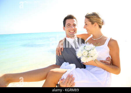 Happy groom holding mariée dans ses bras Banque D'Images