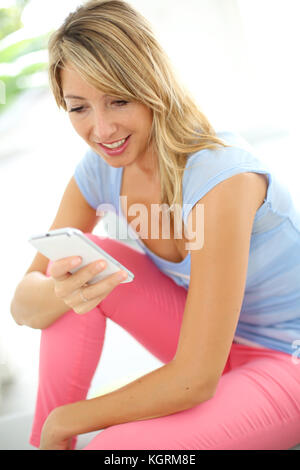 Cheerful blonde woman using mobile phone Banque D'Images