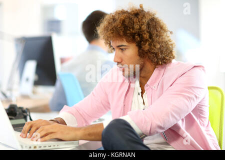 Handsome man in office working on laptop Banque D'Images