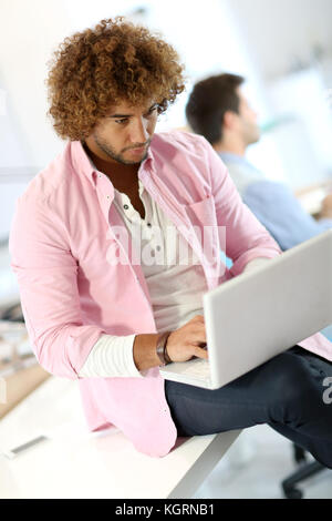 Handsome man in office working on laptop Banque D'Images