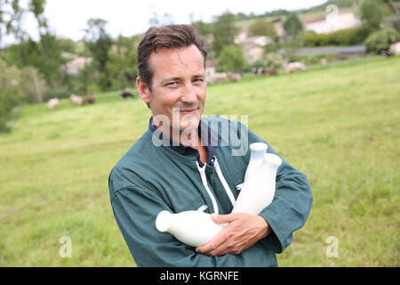 Farmer in field holding bouteilles de lait Banque D'Images