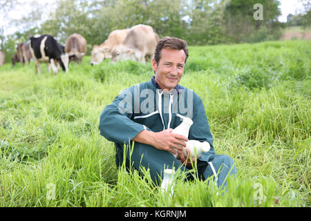 Farmer in field holding bouteilles de lait Banque D'Images