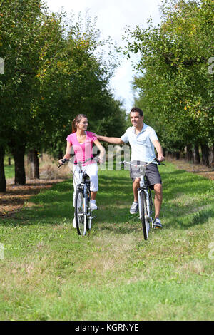 Cheerful young couple riding bikes in countryside Banque D'Images