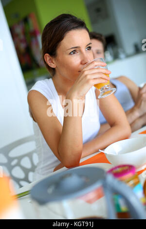 Fille brune profiter de jus d'orange pour le petit déjeuner Banque D'Images