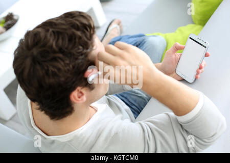 Vue supérieure de l'homme dans sofa using smartphone Banque D'Images