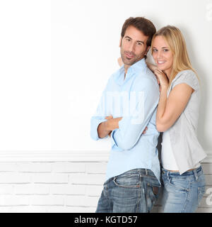 Jeune couple debout sur mur blanc Banque D'Images