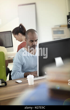 L'homme travaillant sur ordinateur de bureau Banque D'Images