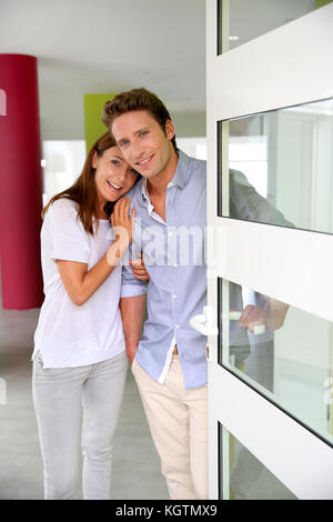 Cheerful couple invitant les gens à entrer dans la maison Banque D'Images