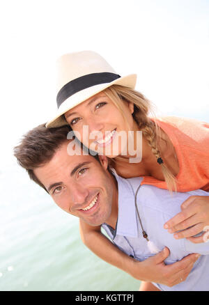 Man giving piggyback ride de belle fille blonde avec chapeau Banque D'Images