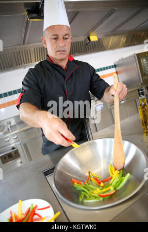 Chef dans une cuisine de restaurant la préparation de légumes au wok Banque D'Images