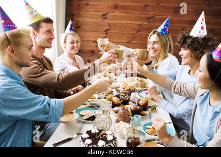 Friendly young people toasting avec plus de boissons servis à table de fête d'anniversaire Banque D'Images