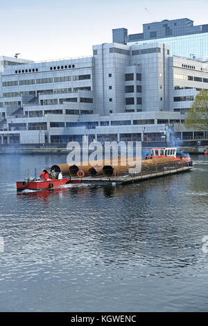 Des carters de pieux en acier de grand diamètre sont livrés à un chantier de construction de Canary Wharf par barge éliminant le besoin de transport routier. Manœuvre Banque D'Images