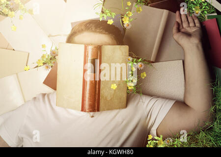 Vue de dessus d'un lecteur qui dort et portant sur les livres et de l'herbe Banque D'Images