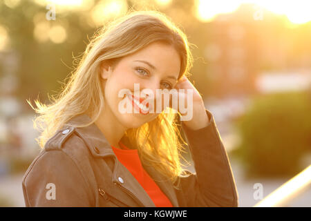 Portrait d'une belle blonde woman posing looking at camera dans un foyer balcon au coucher du soleil Banque D'Images