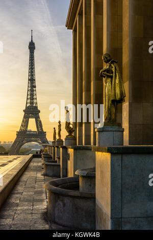 Le soleil illumine les statues en or sur l'esplanade du Trocadéro et la Tour Eiffel se détache sur un ciel orange. Banque D'Images