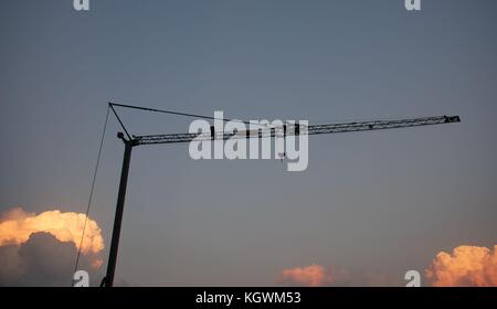 D'une grue sur un chantier est découpé sur les nuages qui sont éclairées par les rayons du soleil définition Banque D'Images