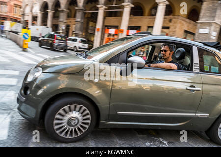 Un jeune homme dans une Fiat 500, Via Zamboni, Bologna city life, en Italie. Banque D'Images