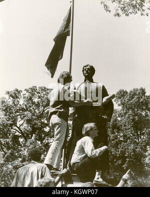 Des étudiants portant une tenue hippie grimpent sur une statue, peut-être un monument confédéré, lors d'une manifestation étudiante anti-guerre du Vietnam à l'Université d'État de Caroline du Nord, Raleigh, Caroline du Nord, 1970. () Banque D'Images