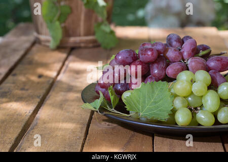 Assiette de raisins rouges et blancs sur une surface en bois Banque D'Images