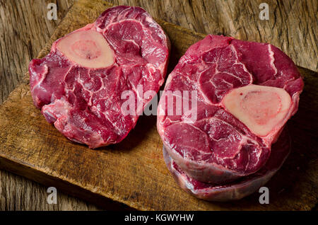 La viande de boeuf cru en coupe croisée pour ossobuco coupe sur un conseil sur fond de bois rustique Banque D'Images