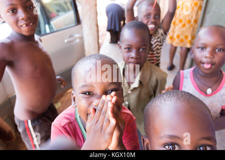 Une bande d'enfants ougandais au hasard dans la rue en riant, souriant, agitant et avoir du plaisir devant la caméra. Banque D'Images