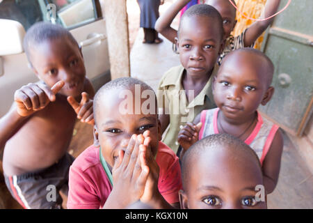 Une bande d'enfants ougandais au hasard dans la rue en riant, souriant, agitant et avoir du plaisir devant la caméra. Banque D'Images