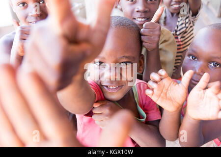 Une bande d'enfants ougandais au hasard dans la rue en riant, souriant, agitant et avoir du plaisir devant la caméra. Banque D'Images