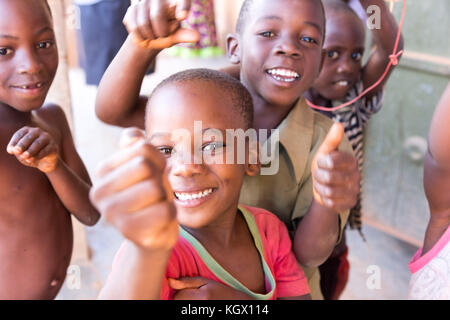 Une bande d'enfants ougandais au hasard dans la rue en riant, souriant, agitant et avoir du plaisir devant la caméra. Banque D'Images