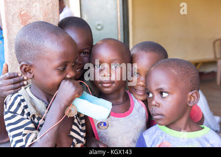 Un groupe d'enfants, rire, gesticulant, s'amusant posant devant la caméra. L'un d'eux est maintenant une simple petite voiture faite d'une bouteille et de bo Banque D'Images