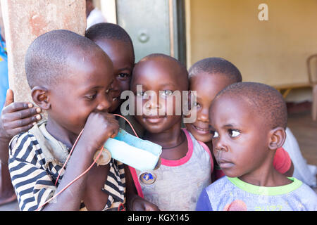 Un groupe d'enfants, rire, gesticulant, s'amusant posant devant la caméra. L'un d'eux est maintenant une simple petite voiture faite d'une bouteille et de bo Banque D'Images