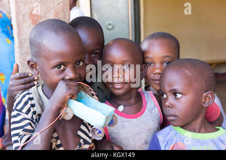 Un groupe d'enfants, rire, gesticulant, s'amusant posant devant la caméra. L'un d'eux est maintenant une simple petite voiture faite d'une bouteille et de bo Banque D'Images