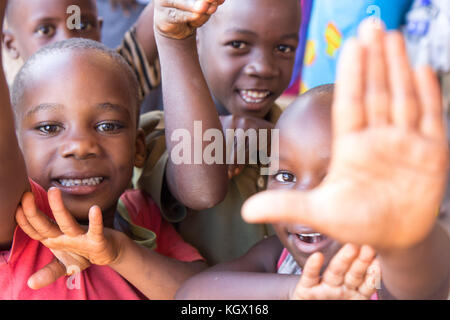 Une bande d'enfants ougandais au hasard dans la rue en riant, souriant, agitant et avoir du plaisir devant la caméra. Banque D'Images