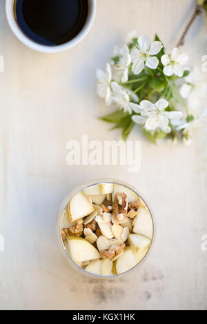 Petit-déjeuner gruau aromatisé avec de la purée de banane, surmonté de tranches de poire, noix, miel et amandes tranchées, vue de dessus, servi dans un round g Banque D'Images