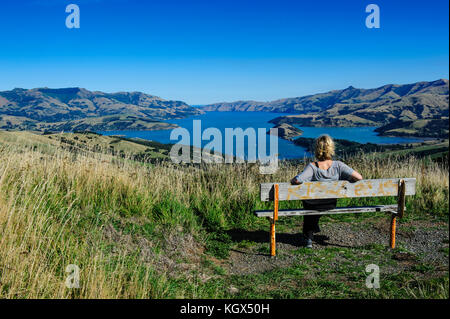 Femme jouissant de la vue sur le magnifique port d'Akaroa, la péninsule de Banks, île du Sud, Nouvelle-Zélande Banque D'Images