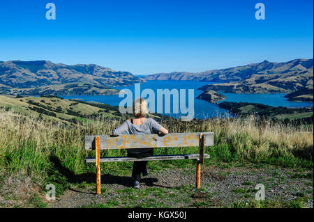 Femme jouissant de la vue sur le magnifique port d'Akaroa, la péninsule de Banks, île du Sud, Nouvelle-Zélande Banque D'Images