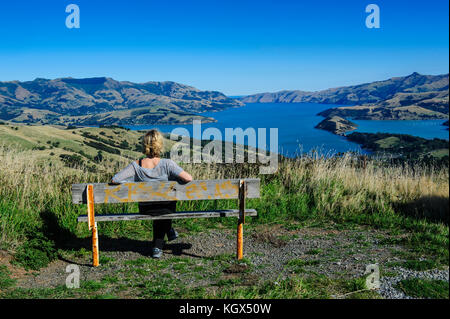 Femme jouissant de la vue sur le magnifique port d'Akaroa, la péninsule de Banks, île du Sud, Nouvelle-Zélande Banque D'Images