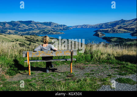 Femme jouissant de la vue sur le magnifique port d'Akaroa, la péninsule de Banks, île du Sud, Nouvelle-Zélande Banque D'Images