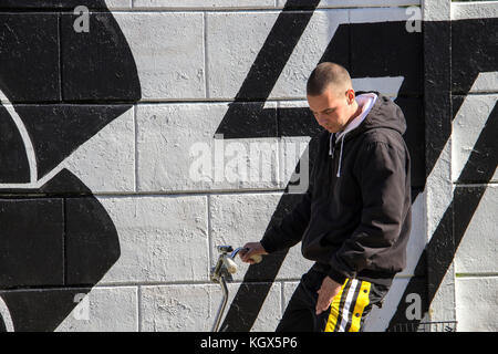 Un jeune homme, gopnik, assis sur un vélo à côté d'un mur recouvert de graffitis Banque D'Images