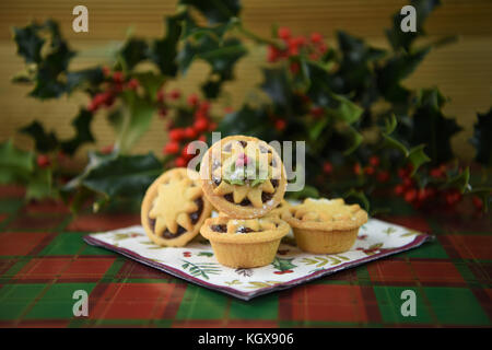 Noël Nourriture photographie image avec des fruits pâtisserie glacé mince pies et star top avec du vrai frais vert de houx et de fruits rouges en arrière-plan Banque D'Images