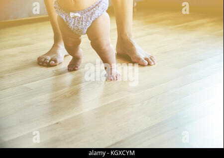 La mère du bébé et les pieds sont sur le sol en bois foor. rêve flou. Banque D'Images