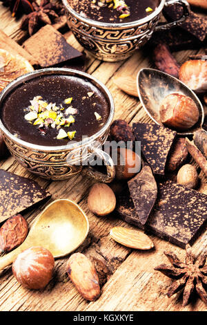 Le chocolat fondu avec des épices dans des tasses en métal élégant Banque D'Images