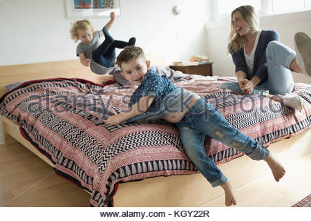 Mère et enfant en fille et son fils jouer, sauter sur le lit